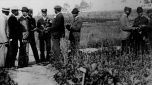 Historic photo of men discussing in rural field.