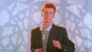 Man singing into microphone with leafy shadow background.