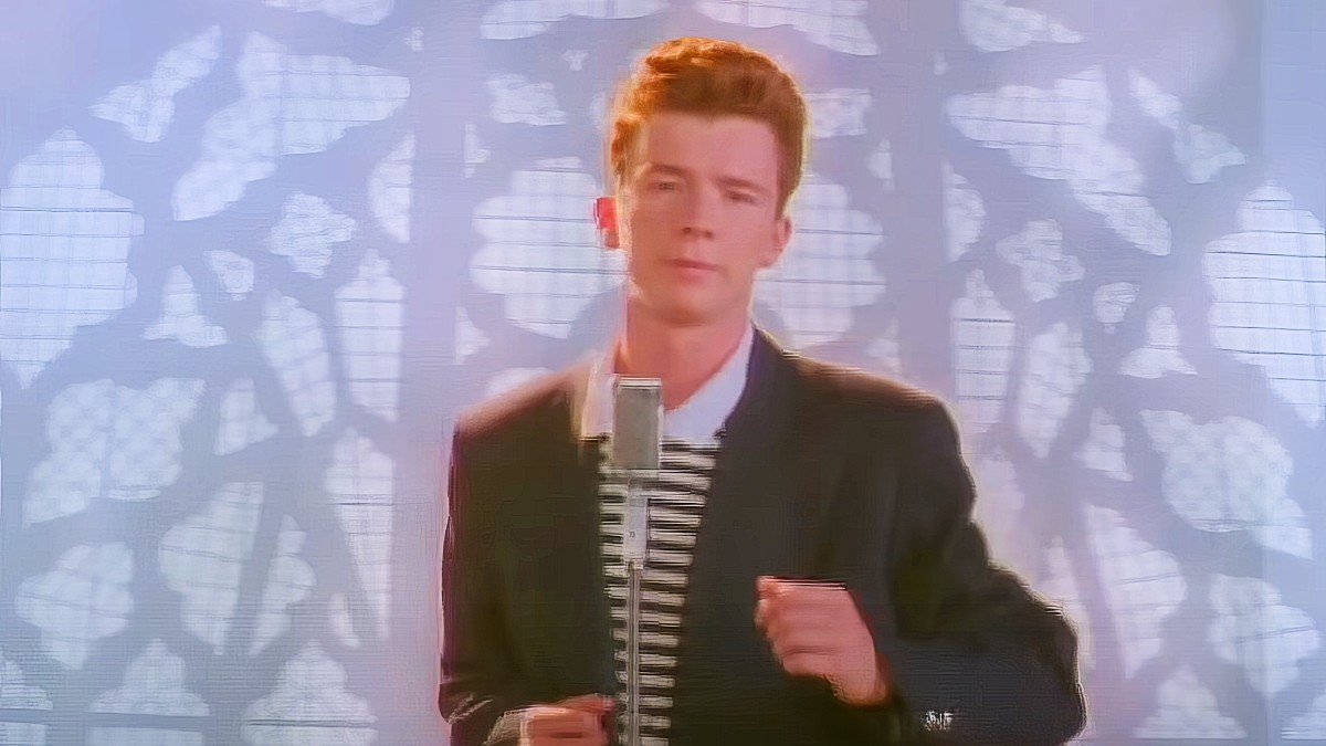 Man singing into microphone with leafy shadow background.